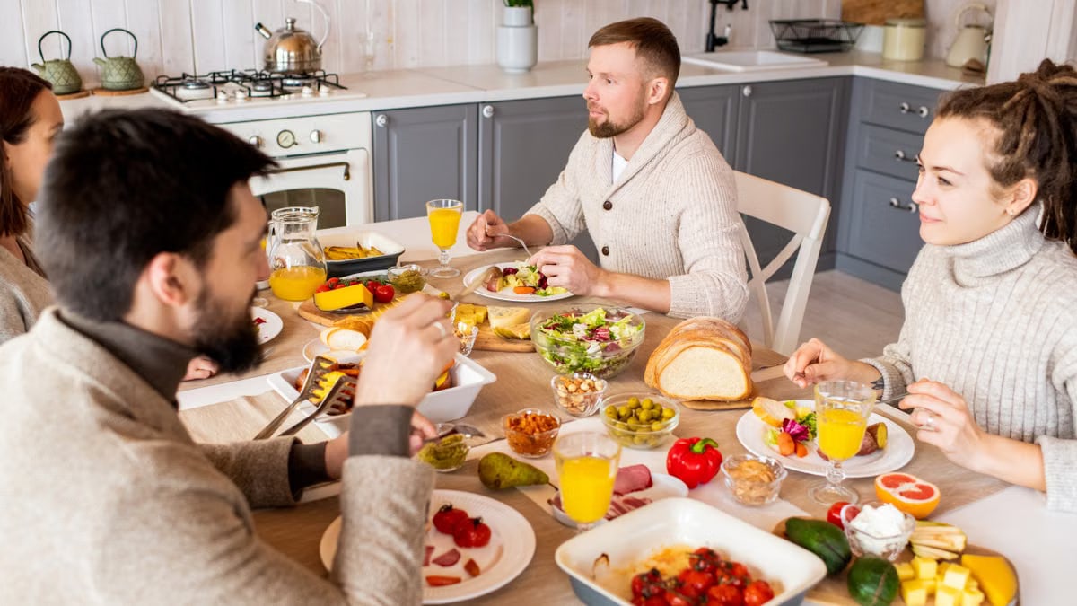 Cozy indoor gathering of friends at a table set with diverse dishes and orange juice.